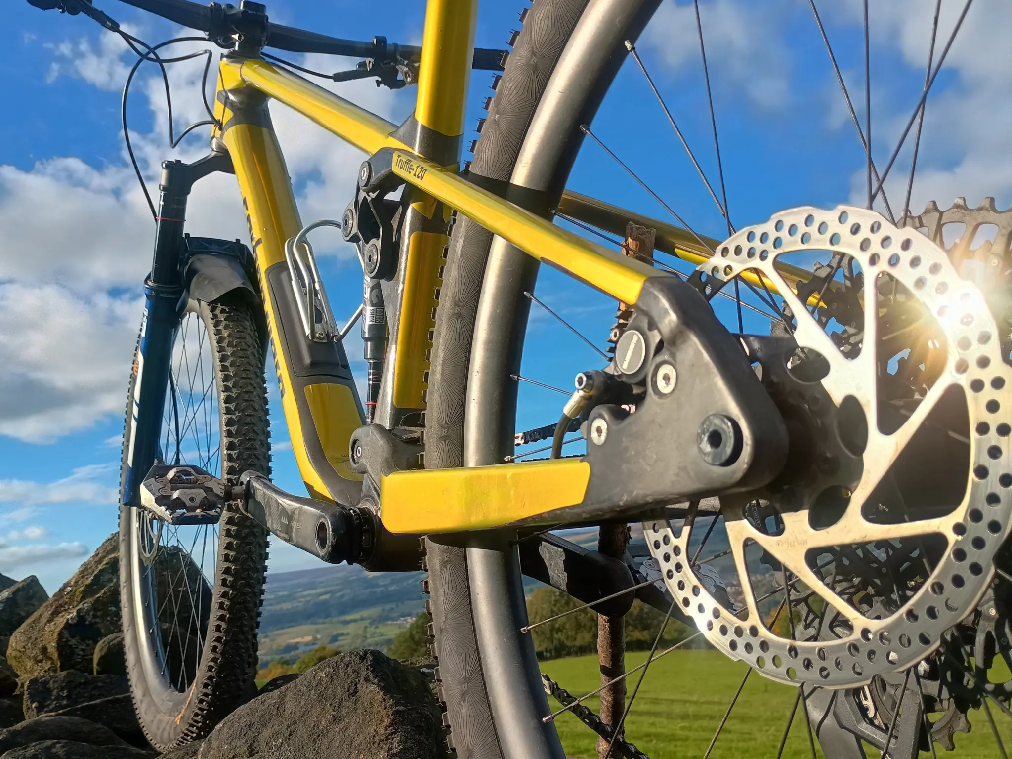 Close-up of the lower part of the yellow frame and the rear brake disc of a Carbon Wasp Truffle-120
